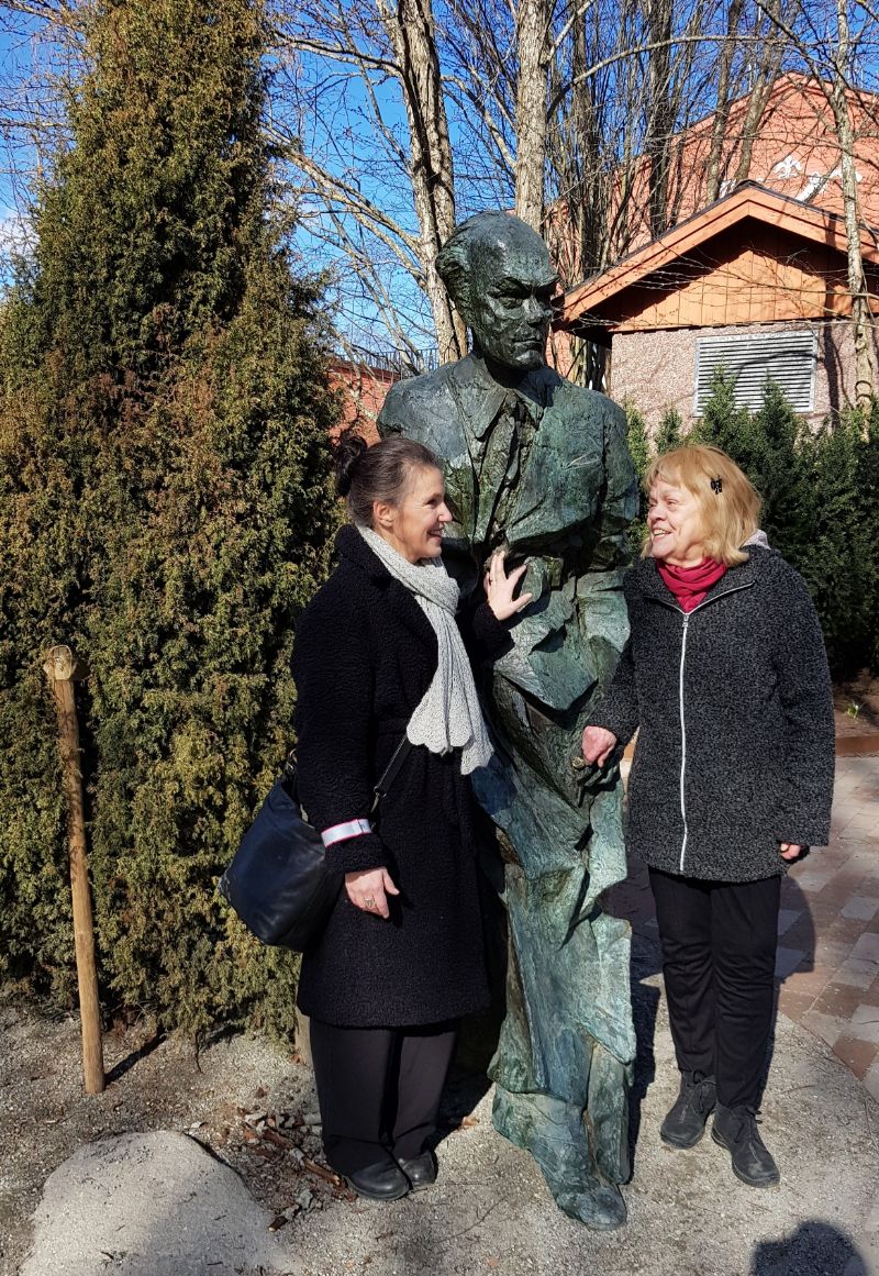 Kristina Sandberg och Aase Fridegård i samspråk vid Jan Fridegårdstatyn den 2 april 2022.